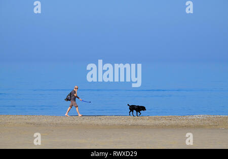 person walking dog on seashore, holkham beach, north norfolk, england Stock Photo