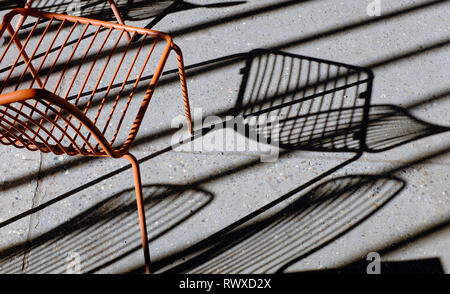 painted metal seat shadows on grey concrete floor Stock Photo