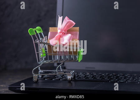 Daily purchases in the shopping cart on the laptop keyboard on a dark background. Concept of shopping in online stores Stock Photo