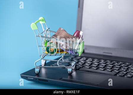Daily purchases in the shopping cart on the laptop keyboard on a blue background. Concept of shopping in online stores Stock Photo