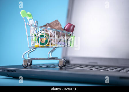 Daily purchases in the shopping cart on the laptop keyboard on a blue background. Concept of shopping in online stores Stock Photo