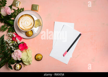 Cup of coffee with flowers on pastel pink background. Copy space. Blank paper on table Stock Photo