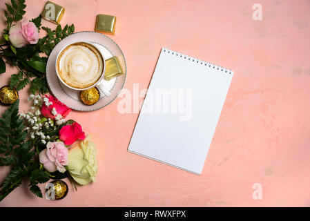Cup of coffee with flowers on pastel pink background. Copy space. Blank paper on table Stock Photo