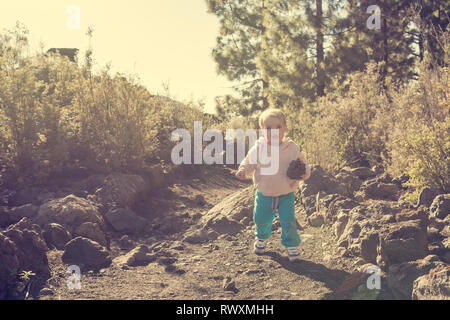 Cute girl walking along forest path and carrying a pine cone. Stock Photo