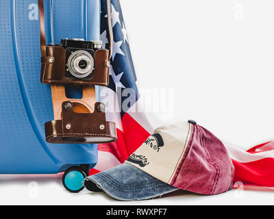 Stylish, blue suitcase, USA flag, vintage camera in a leather case on a white background, isolated. Close-up. Preparing for the summer trip Stock Photo