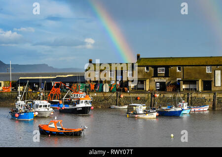 Lyme Regis, Dorset, UK.  7th March 2019. UK Weather.  A rainbow arches over the Cobb Harbour at the seaside town of Lyme Regis in Dorset on an afternoon of sunshine and showers.   Picture Credit: Graham Hunt/Alamy Live News Stock Photo