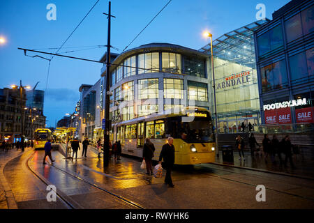 Wet and dark at Exchange Square and Manchester Arndale shopping centre mall entrance as a Metrolink tram departs