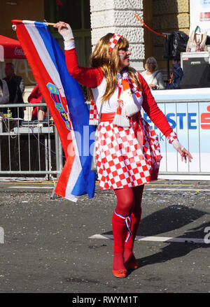 Rijeka, Croatia, March 3rd, 2019. Croatian flag in hand of masked woman dressed in the costume with Croatian national pattern and posing on the street Stock Photo