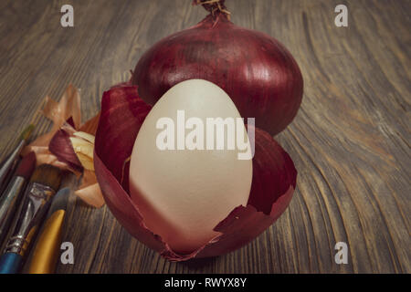Fresh whole red onion, egg and dried onion skin isolated on white. Making Easter eggs dyed with onion skins concept Stock Photo