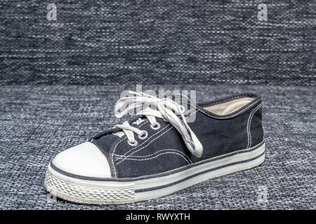 An old all-star shoes that was once quite popular on a textile background Stock Photo