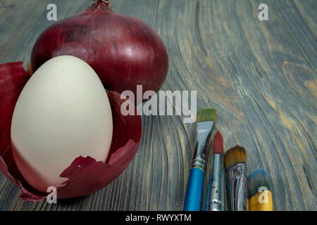 Fresh whole red onion, egg balancing in a dried onion skin. Making natural colored Easter eggs conceptual image Stock Photo