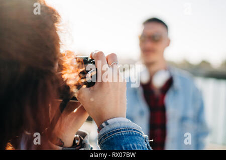 Young photographer woman making photo to young man. Happy Couple on holiday. Stock Photo