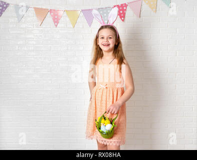 Cute happy girl wearing bunny ears and with Easter decorations on white background Stock Photo