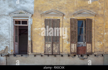 Aged abandoned retro vintage grunge house facade with broken windows and weathered shutters Stock Photo