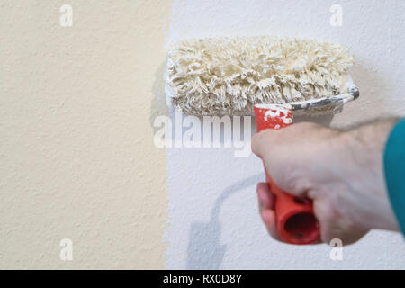male hand painting wall with lambskin roller Stock Photo