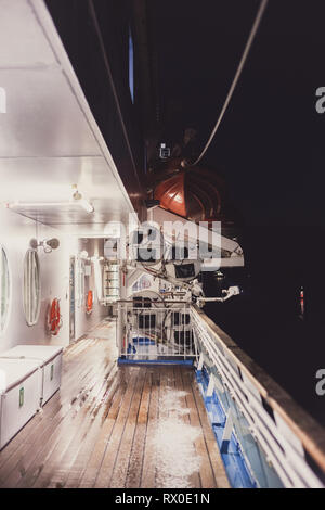 Empty wooden deck and railing with a life ring hanging on the rail on a ...