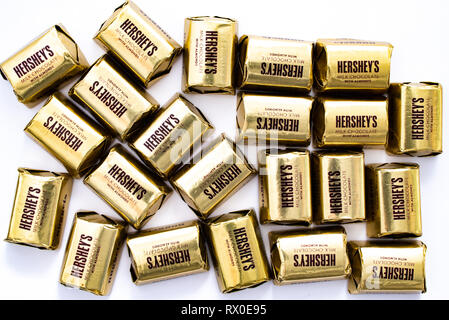 A pile of Hershey's Milk Chocolate with Almonds Nuggets in individual gold colored wrappers isolated on white. Stock Photo