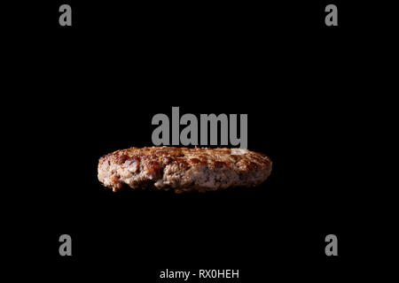 floating grilled burger patty isolated black back Stock Photo