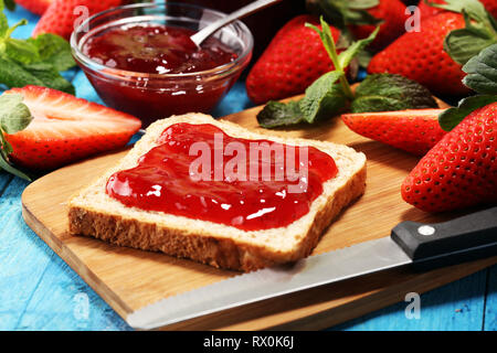 Toast bread with homemade strawberry jam or marmalade on rustic blue table served with butter for breakfast or brunch Stock Photo