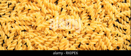 Italian food. Uncooked dry fusilli spiral shape pasta texture background, banner Stock Photo