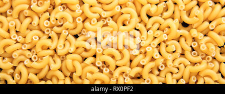 Italian food. Uncooked dry macaroni elbow shape pasta texture background, banner Stock Photo