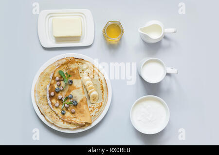 Crepes, thin russian pancakes on a white plate. Pastel blue background. View from above. Stock Photo
