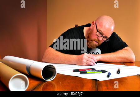 Man concentrating on writing or drawing at a table in warm sunlight ...