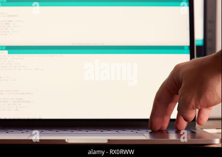 Hand press enter button on blurred screen with code background Stock Photo