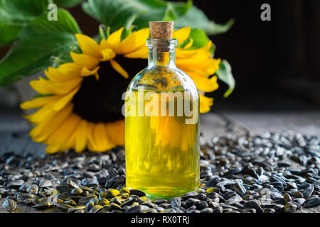 Bottle of sunflower oil, seeds and beautiful yellow sunflower on background. Stock Photo