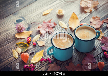 Coffee in blue enameled cups and autumn leaves on wooden desk. Retro toned. Stock Photo