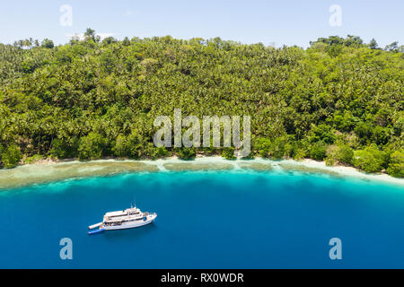 A small dive boat is anchored off the coast of Papua New Guinea. This tropical area is part of the Coral Triangle due to its high marine biodiversity. Stock Photo