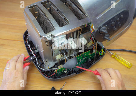 Concept Right to Repair, image showing hands of consumer repairing toaster with tools. Reduce waste by repairing household appliances. Stock Photo