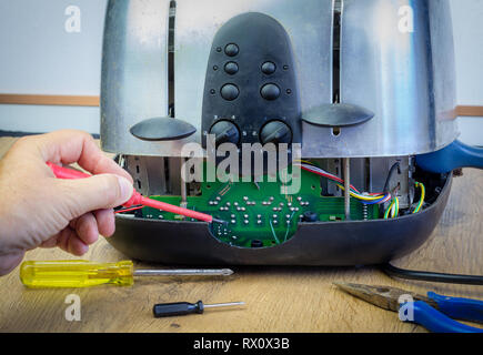 Concept Right to Repair, image showing hands of consumer repairing toaster with tools. Reduce waste by repairing household appliances. Stock Photo