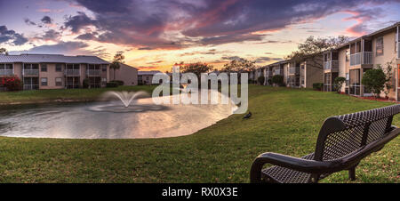 Bench overlooking a large pond with a fountain at sunset in Atlanta, Georgia Stock Photo