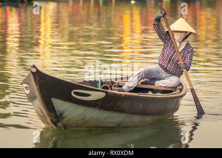 Hoi An city, boats and river landscape at sunset, Vietnam travel destination. Vietnamese woman paddling in a boat on the river Stock Photo