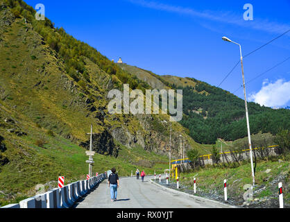 Kazbegi, Georgia - Sep 24, 2018. People walking on mountain road in Kazbegi, Georgia. Stock Photo