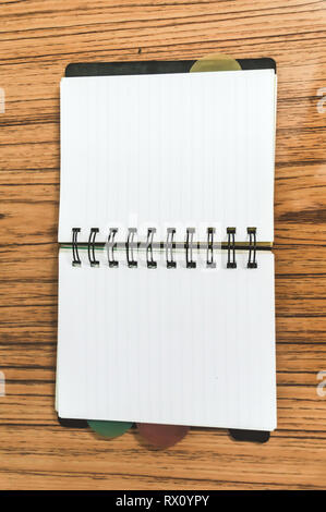 Blank empty notepad on a wood table. Top view image of open pocket planner notebook with empty pages ready for adding text or mockup. Stock Photo