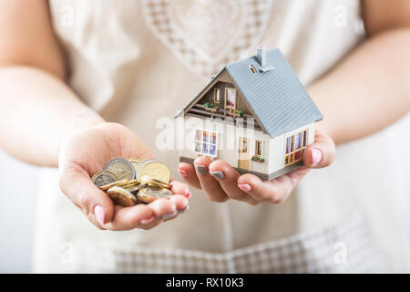 Hands of young hosewife holding model house and euro coins. Stock Photo
