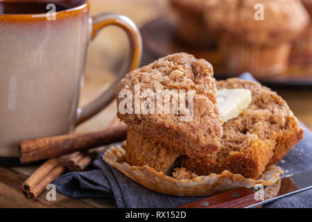 Closeup of a cinnamon muffin cut in half with cup of coffee and muffins in background Stock Photo
