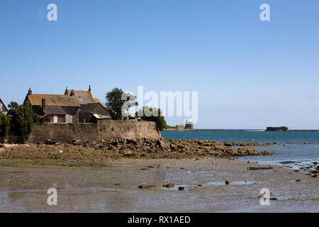 Cottage by the sea, with Ile de Tatihou and le Tour Vauban beyond,  St Vaast la Hougue, Normandy, France Stock Photo