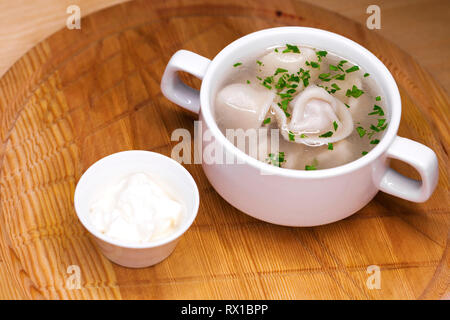 Russian national dish - boiled dumplings with broth in a white cup Stock Photo