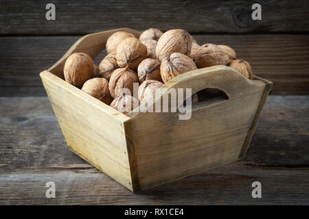 Walnuts in a wooden crate on wooden table. Stock Photo