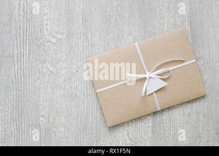 Envelope from brown craft paper decorated with ribbon and label on gray wooden background with copy space. Stock Photo