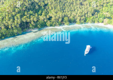 A small dive boat is anchored off the coast of Papua New Guinea. This tropical area is part of the Coral Triangle due to its high marine biodiversity. Stock Photo