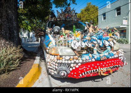 KEY WEST, FLORIDA, USA - JANUARY 14, 2019: A car decorated with a unique mix of shells and figurines stands parked on a quiet residential street. Stock Photo