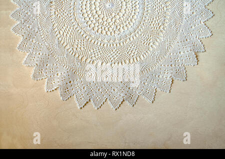 Border made of openwork white napkin knitted of thin cotton threads lying on top of light plywood Stock Photo