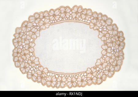 Oval openwork white napkin with cream flowers on the edge of the cotton thread, lies on a white background Stock Photo
