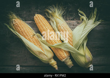 Yellow sweet corn cobs on wooden board, top view. Stock Photo