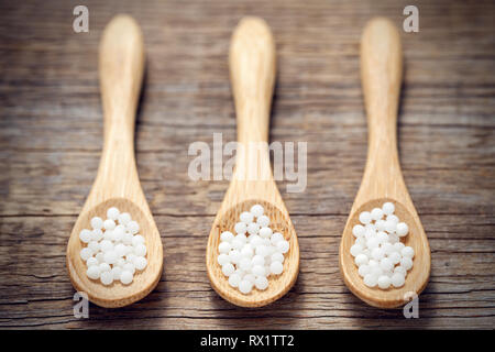 Three woodens spoon of homeopathic globules. Homeopathy medicine. Stock Photo