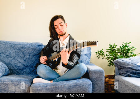 Young guitarist learning to play the guitar in his living room. Stock Photo